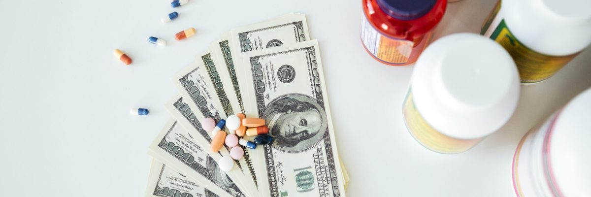 Picture of money with pills and vitamins over white background